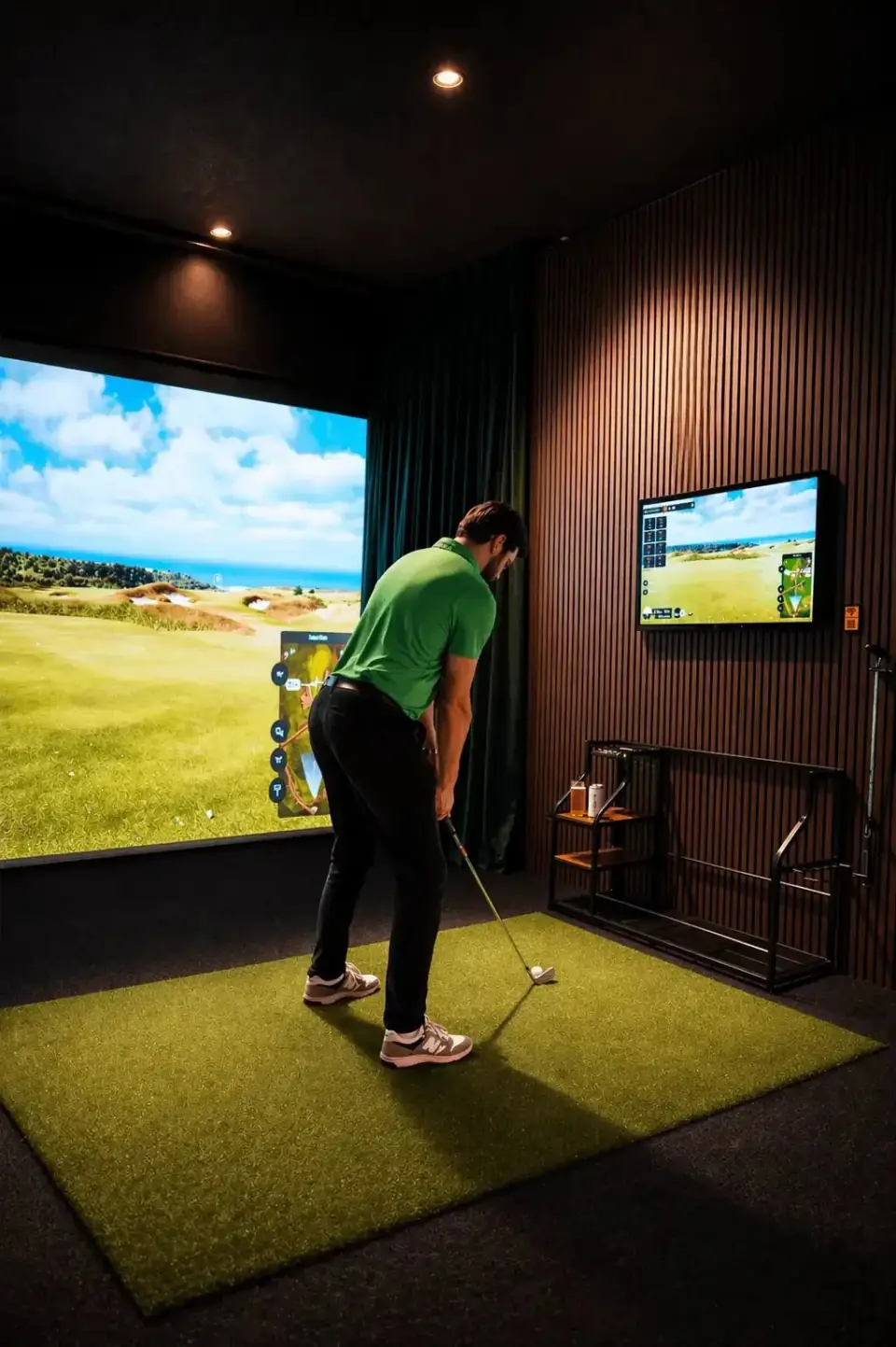 Golfer taking a full swing inside a premium TrackMan golf simulator.